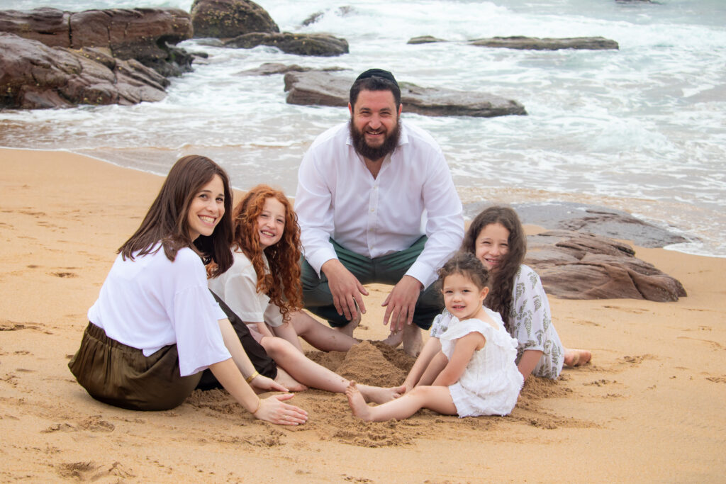 Family group with Mom and Dad and sisters playing in the sand on the beach