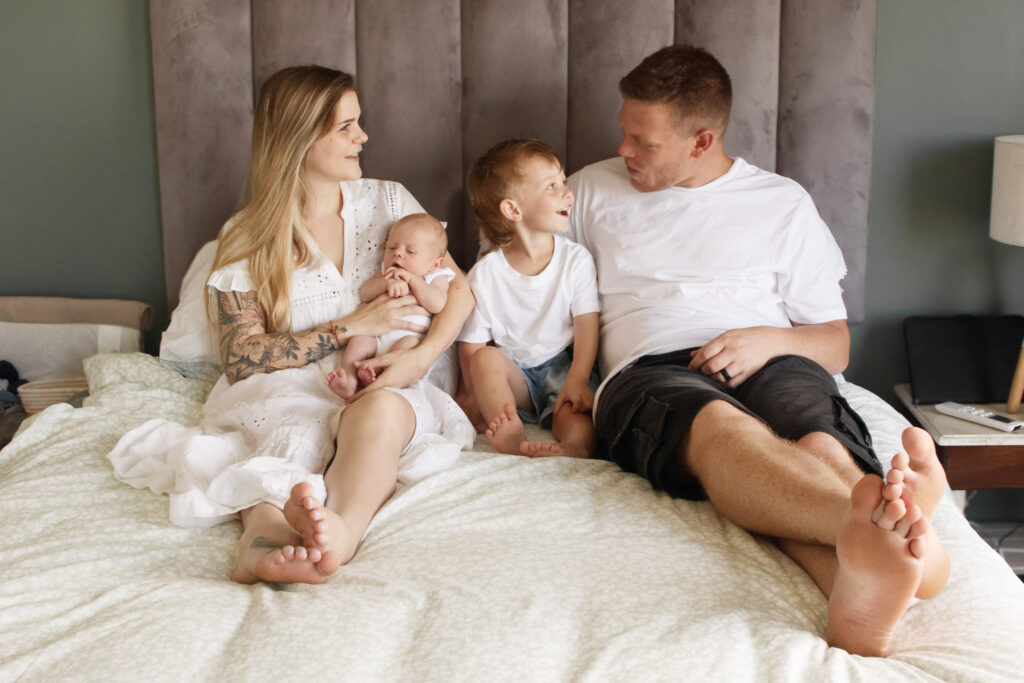 Wichura Family Session of 4 people sitting on the bed together laughing by Pastel Projects Photography